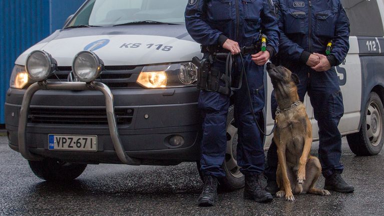 Poliisikoira ja -auto sekä kaksi poliisia.