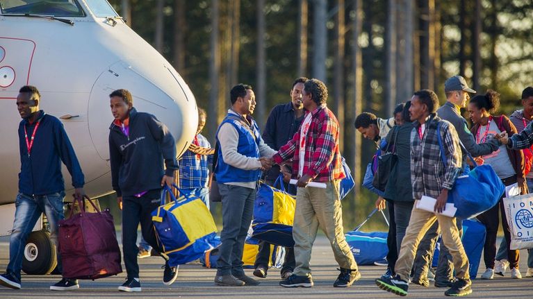 Eritrealaisia turvapaikanhakijoita Luulajan lentokentällä lentokoneen edustalla.