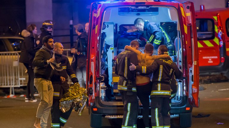 Pelastushenkilöstö saattaa ampumavälikohtauksessa loukkaantuneita ihmisiä ambulanssiin Pariisin keskustassa myöhään perjantai-iltana.