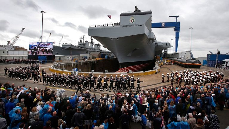 Ihmisiä Britannian rakenteilla olevan uuden Queen Elizabeth -lentotukialuksen ympärillä sen telakalla Skotlannissa heinäkuussa 2014.
