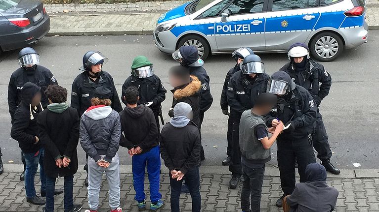poliisi laittaa tapelleita pakolaisia käsirautoihin