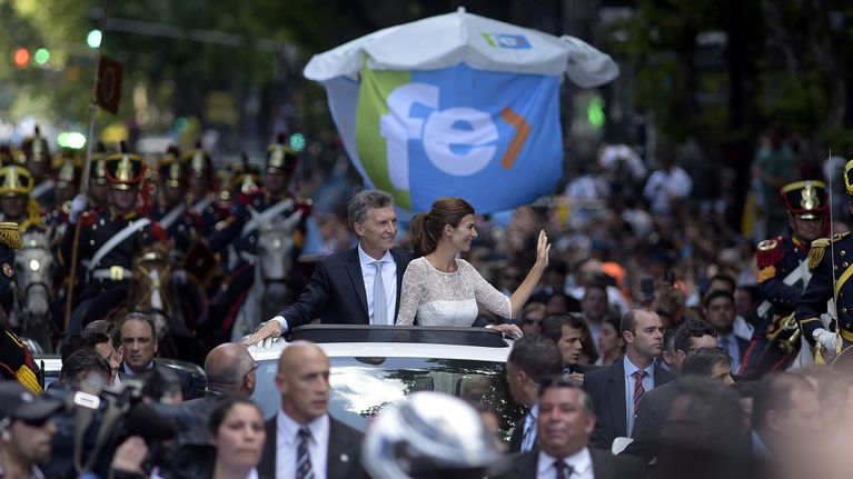 Presidentti Mauricio Macri ja puolisonsa Juliana Awada seisovat autossa, joka kulkee suuren ihmisjoukon keskellä.