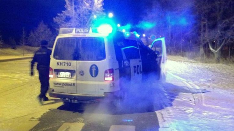 Poliisiautossa vilkut päällä ja kaksi miestä nousemassa autoon