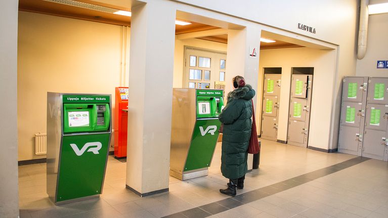 Nainen asioi lipunmyyntiautomaalilla