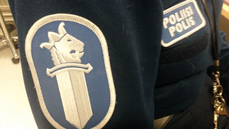 Poliisin hihamerkki ja poliisimerkki sinisessä virka-asussa.