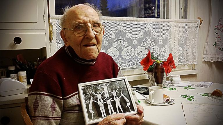Vanhus ja kehystetty kuva käsissään.