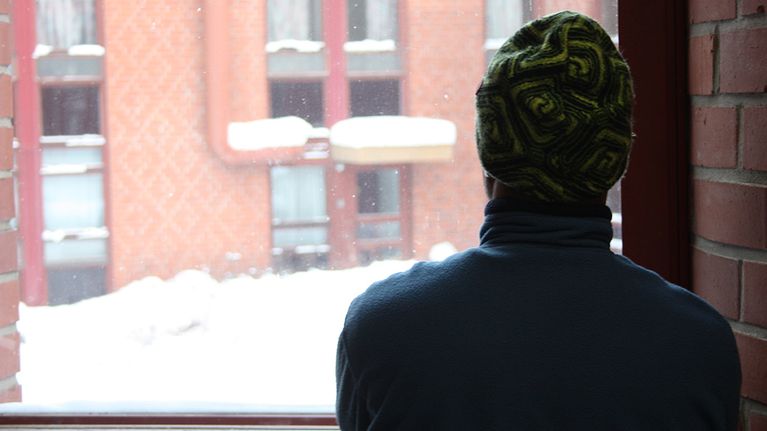mies katselee ikkunasta lunta