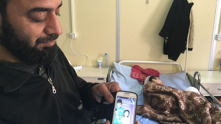Shayma-tytön isä näyttää kuvaa ajasta, jolloin kaikki oli hyvin. Kilis, Turkki. Pommitukset tapahtuivatAleppossa Syyriassa. 