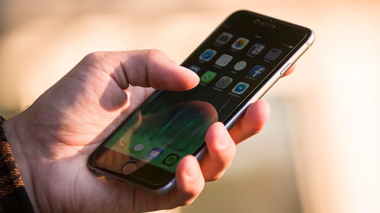 Miehen kädessä älypuhelin jossa näkyy sosiaalisen median appseja.