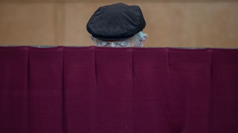 Mies äänestämässä verhon takana.