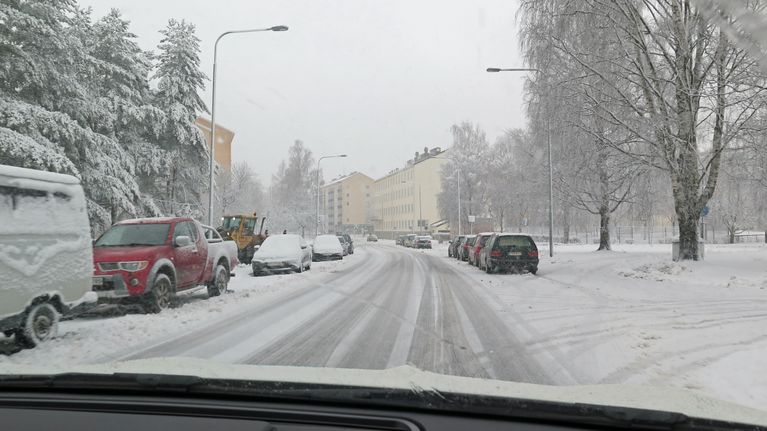 Luminen tie, jonka varrelle on pysäköity autoja