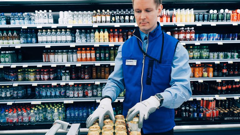 Marketpäällikkö täyttää juomahyllyjä.