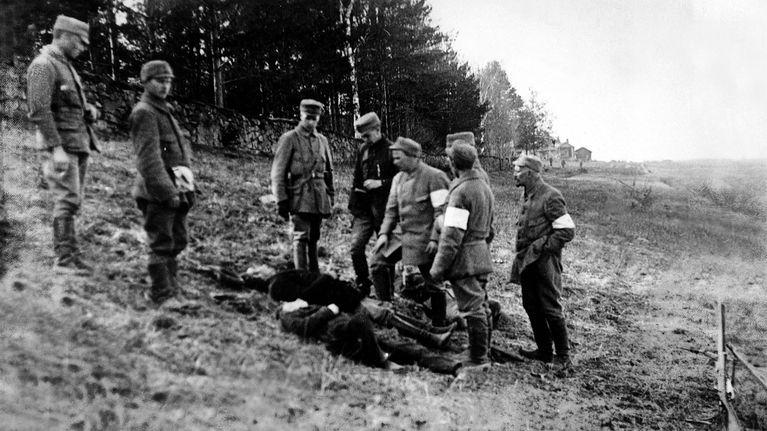 Pohjois-Savon rykmentin suojeluskuntalaiset tarkastelevat teloittamiensa punakaartilaisten ruumiita.