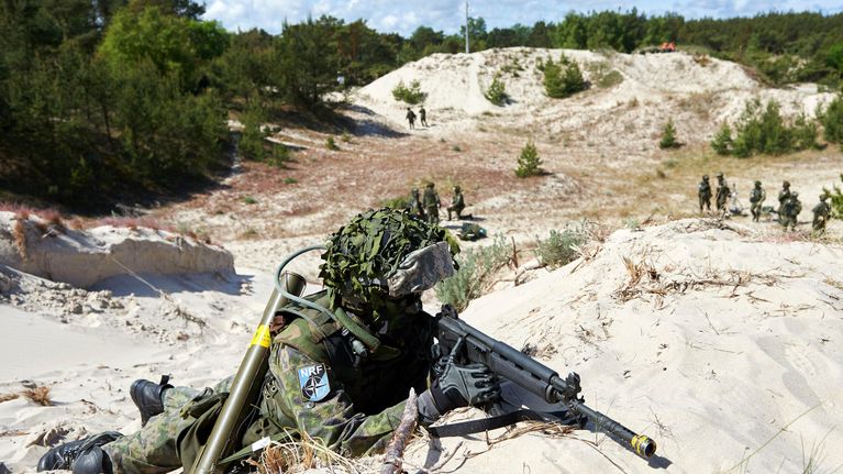 sotilas rynnäkkökivääreineen hiekkadyynillä