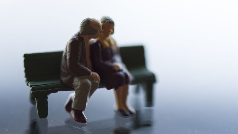 Kaksi miniatyyrihahmoa jotka esittävä vanhaa pariskuntaa puiston penkillä.
