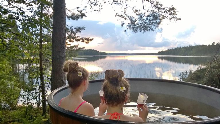 Kaksi naista kylpypaljussa järvenrannassa