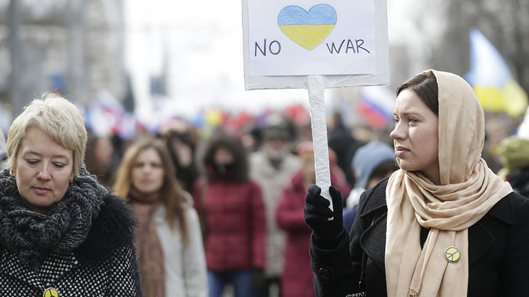 Nainen pitelee No war -kylttiä.