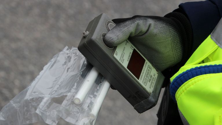 Poliisin kädessä alkometri ja puhallutuspillejä.