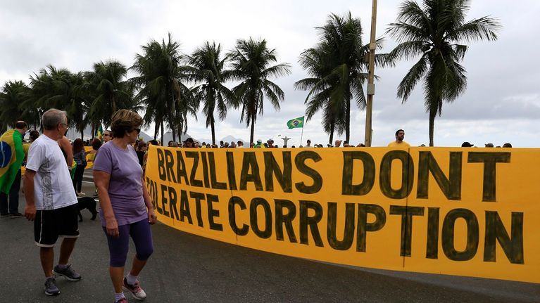 Keltainen lakana jossa lukee "brazilians don't tolerate corruption". Takana palmuja.