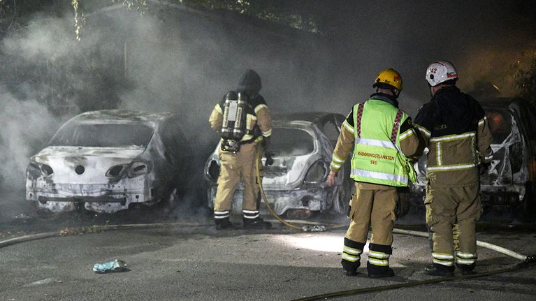 Palomiehiä sammutettujen autojen vieressä Malmössä maanantaina 15. elokuuta.