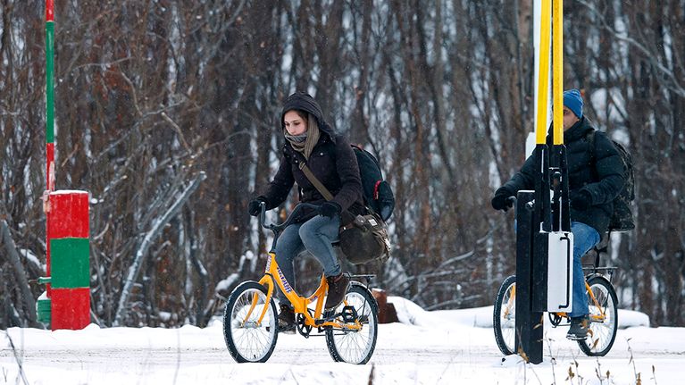 Kaksi pakolaista käyttää polkupyörää ylittäessään rajan Venäjältä Norjaan.