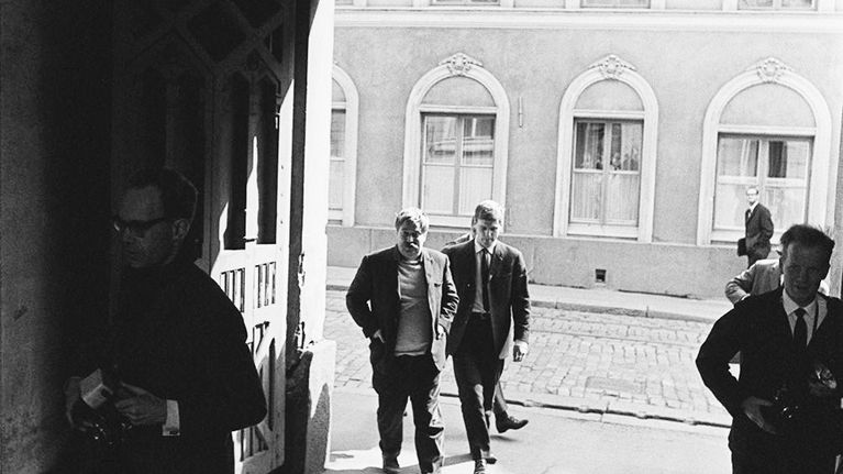 Jumalanpilkkaoikeudenkäynti Helsingin raastuvanoikeudessa. Kirjailija Hannu Salama ja Kustannus Oy Otavan toimitusjohtaja Kari Reenpää vastaamassa oikeudessa "Juhannustanssit"-romaanista nostettuun jumalanpilkkasyytteeseen. Hannu Salama raastuvan portilla, rinnalla juoksee lehtikuvaajia.