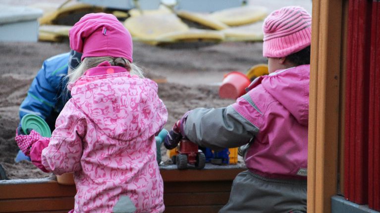 Lapsia tarhassa hiekkalaatikolla. 