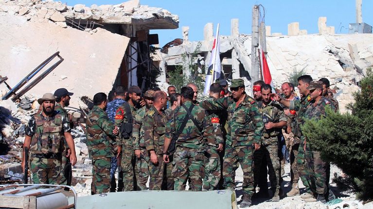 Joukko Syyrian armeijan sotilaita Aleppossa, taustalla rakennusten raunioita.