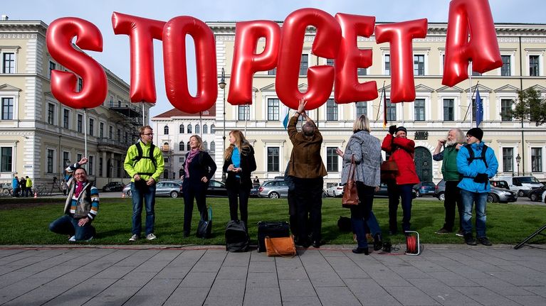 Pieni joukko mielenosoittajia, jotka pitelevät punaisia kirjaimen muotoisia ilmapalloja, jotka muodostavat lauseen Stop CETA.