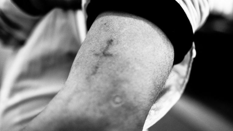 John tatuoi ristin käsivarteensa Bagdadissa. Kun hänen perheensä näki sen, he vaativat Johnia poistamaan tatuoinnin. John on joutunut katkaisemaan siteensä perheeseensä uskonnon hylkäämisen vuoksi.