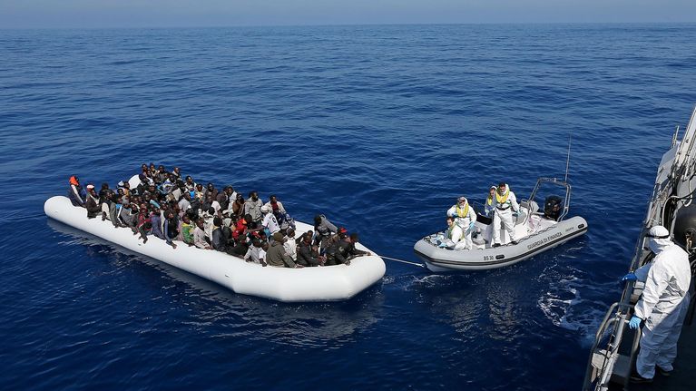 Italian viranomaiset pelastamassa pakolaisia kumiveneestä.