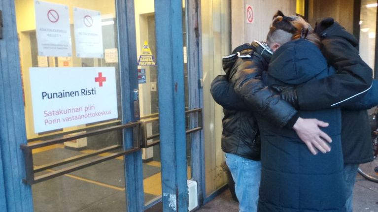 Sangar, Kristina ja Harri halaavat vastaanottokeskuksen ovella