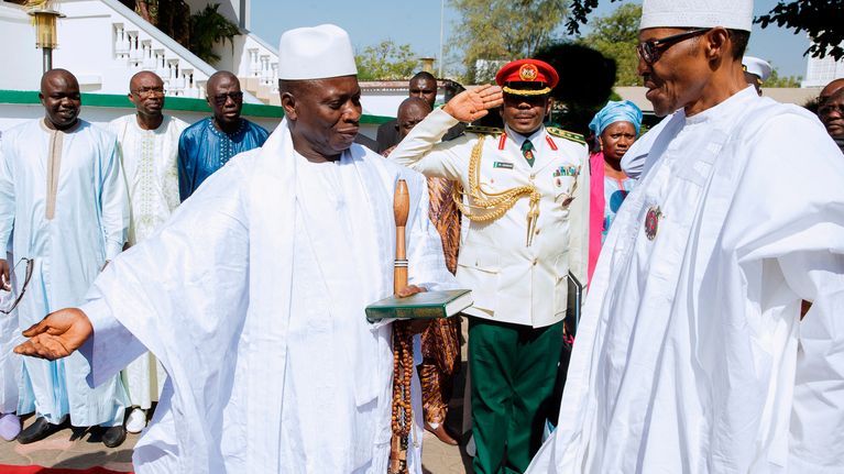 Valkoasuiset Jammeh ja Buhari seisovat ulkona punaisella matolla. Taustalla muita ihmisiä.