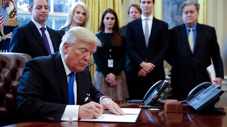 Donald Trump kuvattuna taustajoukkoineen Valkoisessa talossa 24. tammikuuta 2017.