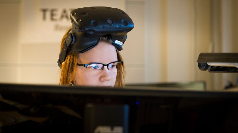 Naine virtuaalilasit otsalla tietokoneen ääressä.