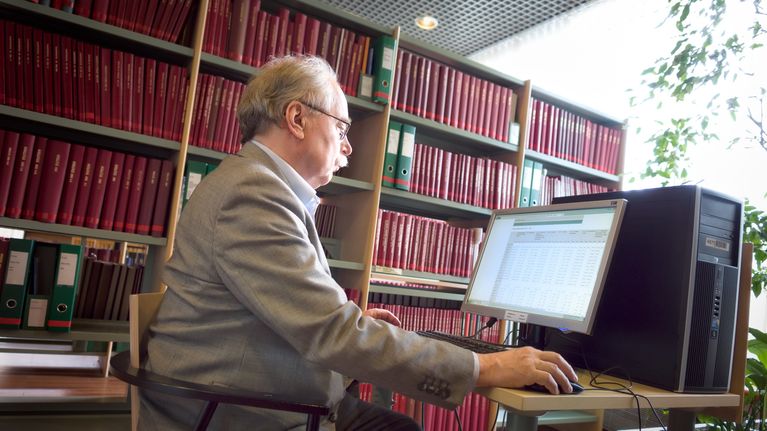 Ilkka Lehtinen asettui kuvattavaksi Tilastokeskuksen kirjastoon.