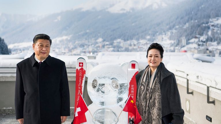 Xi Jinping seisoo vaimonsa kanssa jääveistoksen vieressä lumisessa maisemassa. 