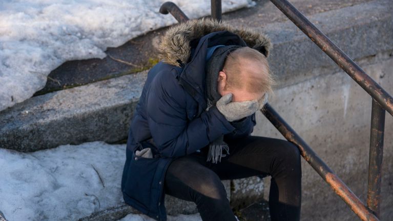 Mies istuu portailla kasvot haudattuna käsiin.