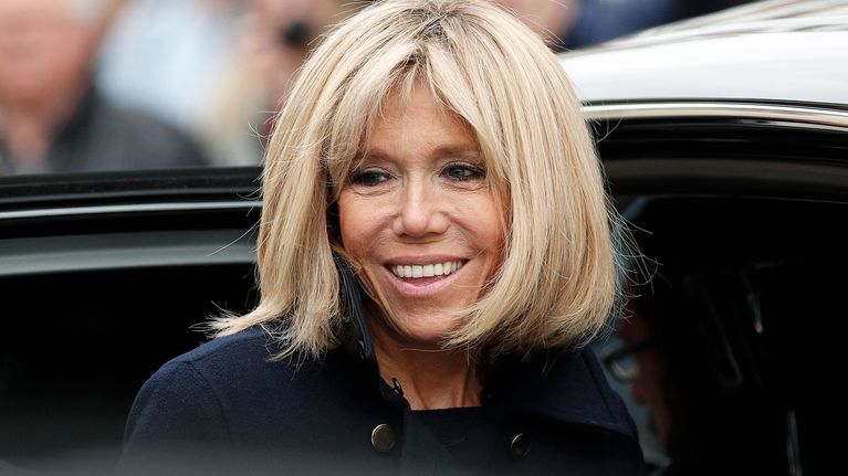 Brigitte Trogneux nousemaassa auton kyytiin hymyillen kameroille.