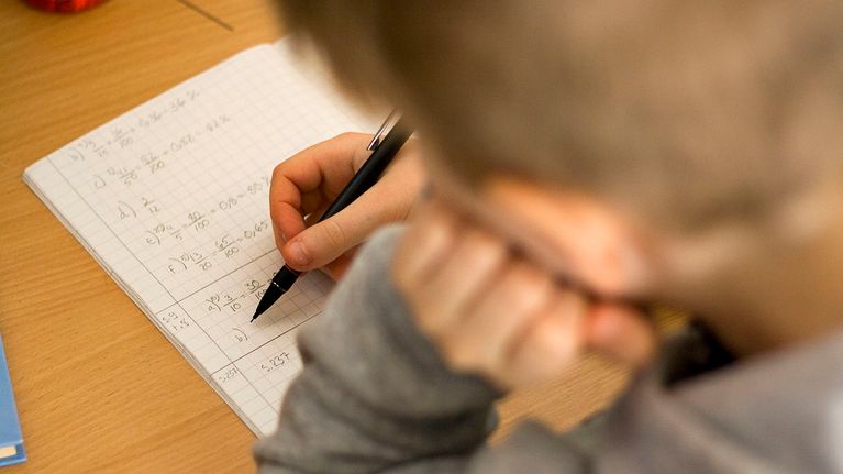 Lapsi laskee matematiikan tehtäviä.
