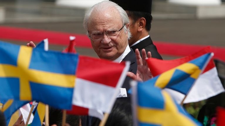 Kuningas vilkuttaa lapsille, jotka heiluttavat Ruotsin ja Indonesian lippuja. 
