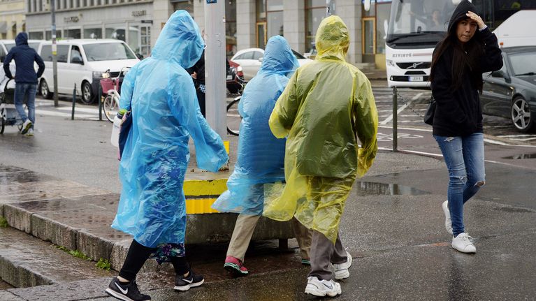 Turisteja kertakäyttösadetakeissaan Kauppatorilla Helsingissä.