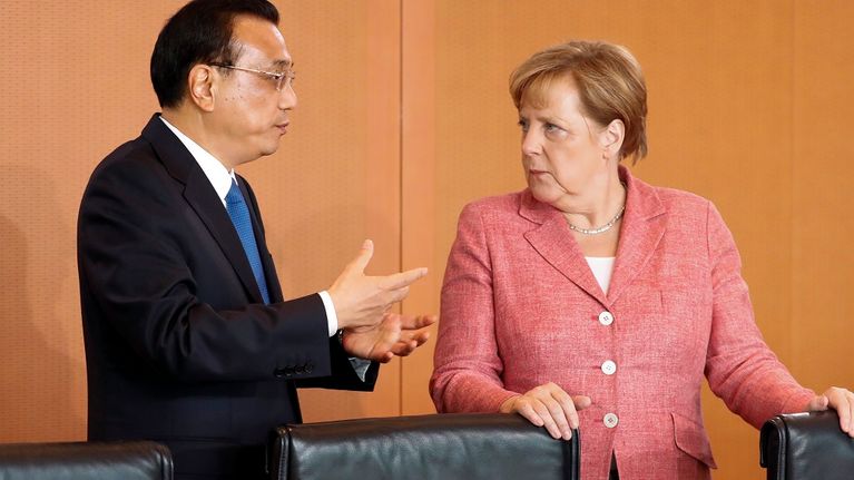 Li Keqiang elehtii käsillään, Merkel katsoo vakavana.