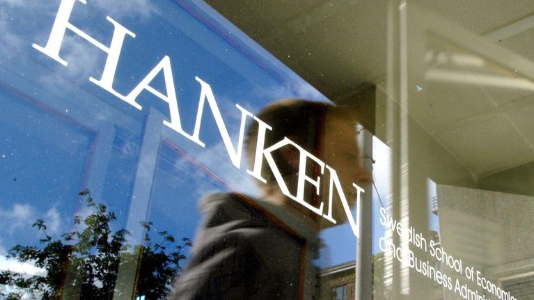 Glasdörr med Svenska handelshögskolans logo och reflektionen av en elev